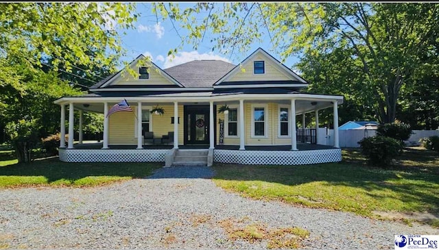 farmhouse featuring covered porch, fence, and a front lawn