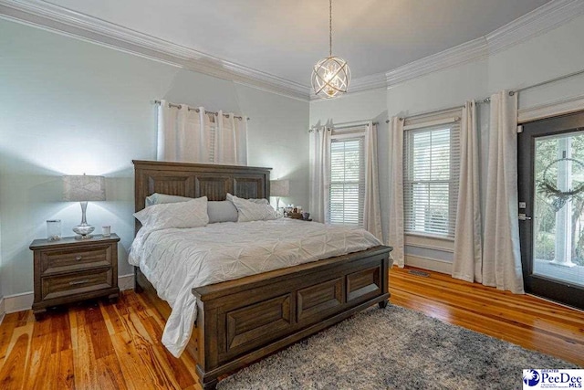 bedroom with visible vents, baseboards, crown molding, and wood finished floors