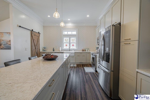 kitchen featuring light stone countertops, ornamental molding, a barn door, appliances with stainless steel finishes, and dark wood-style floors