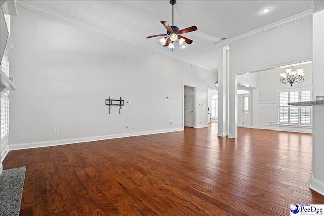 unfurnished living room featuring ceiling fan with notable chandelier, wood finished floors, baseboards, and ornamental molding