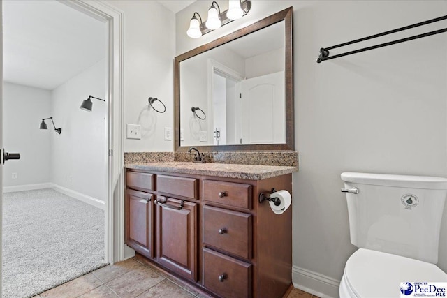 half bath featuring tile patterned floors, toilet, vanity, and baseboards