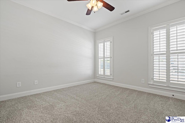 carpeted spare room featuring crown molding, baseboards, visible vents, and ceiling fan