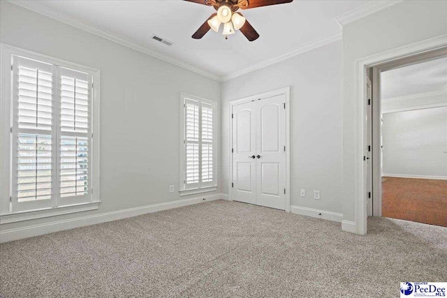 unfurnished bedroom with visible vents, carpet flooring, crown molding, and baseboards