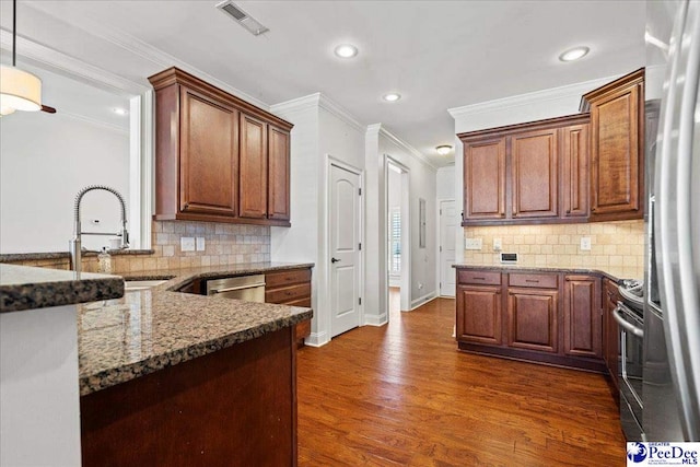 kitchen featuring visible vents, a sink, dark stone countertops, appliances with stainless steel finishes, and dark wood-style flooring