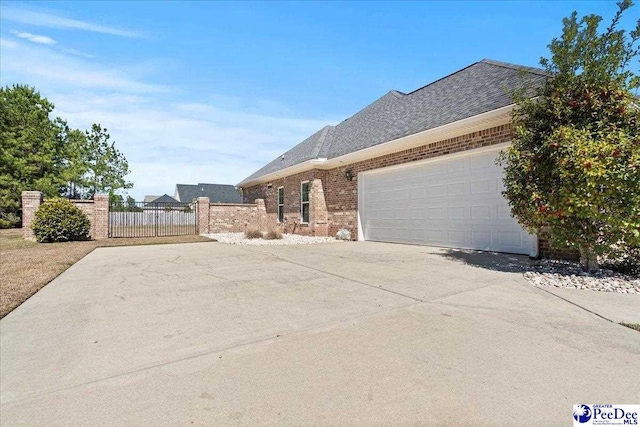 view of property exterior with brick siding, a shingled roof, fence, concrete driveway, and an attached garage