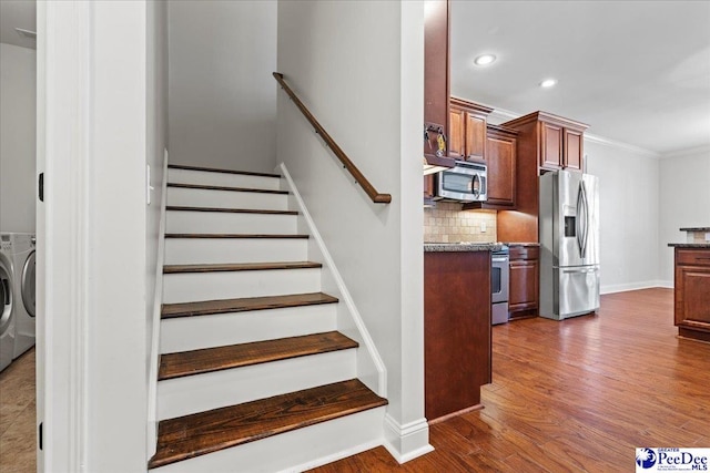 staircase with washer and clothes dryer, wood finished floors, recessed lighting, crown molding, and baseboards