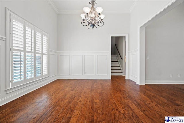 empty room featuring dark wood finished floors, a chandelier, stairway, and ornamental molding