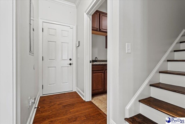 corridor with stairway, baseboards, dark wood-type flooring, and crown molding