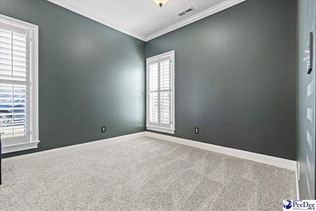 carpeted spare room featuring visible vents, baseboards, and ornamental molding