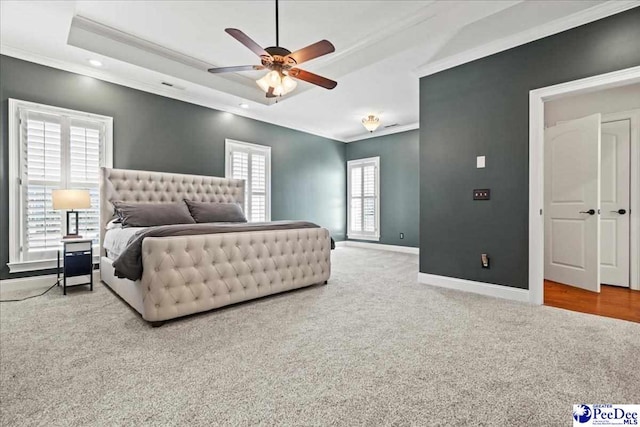 carpeted bedroom featuring baseboards, a raised ceiling, ceiling fan, and crown molding