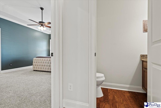 bathroom featuring toilet, a ceiling fan, wood finished floors, baseboards, and vanity