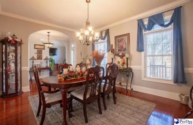 3438 Hammock Ct, Florence, SC 29501 - dining area featuring a notable chandelier, wood finished floors, arched walkways, baseboards, and ornamental molding