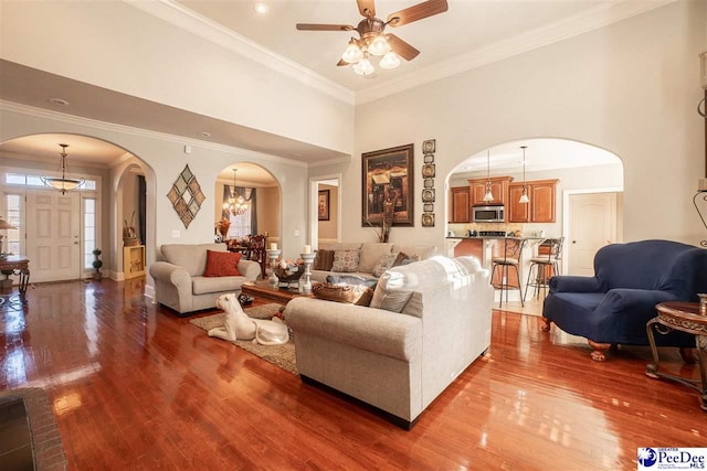3438 Hammock Ct, Florence, SC 29501 - living room featuring crown molding, wood finished floors, ceiling fan with notable chandelier, arched walkways, and a towering ceiling