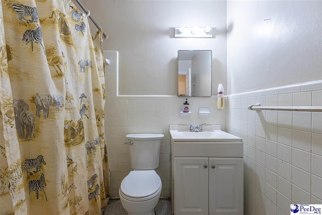 bathroom with vanity, toilet, a shower with shower curtain, and tile walls