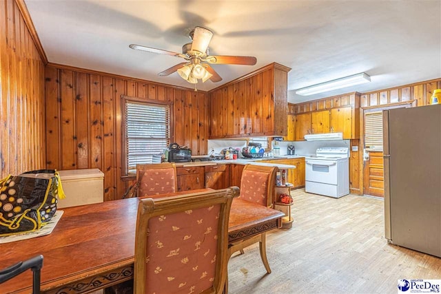 kitchen featuring electric stove, stainless steel fridge, ceiling fan, wooden walls, and light wood-type flooring