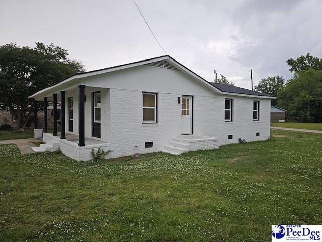 view of side of property with a yard and covered porch