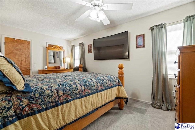 bedroom featuring a textured ceiling, ceiling fan, multiple windows, and carpet flooring