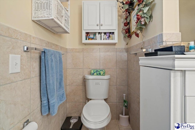 half bath featuring toilet, a wainscoted wall, and tile walls