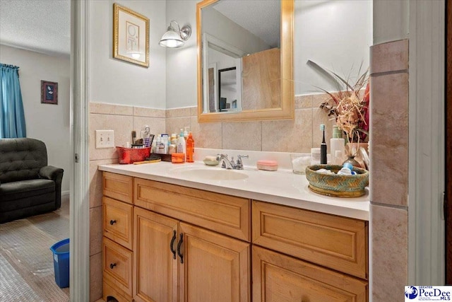 bathroom with wainscoting, tile walls, vanity, and a textured ceiling