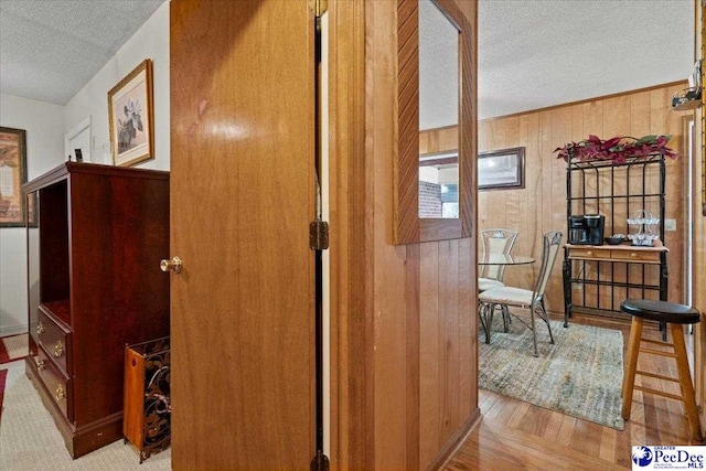 hall with a textured ceiling and wooden walls