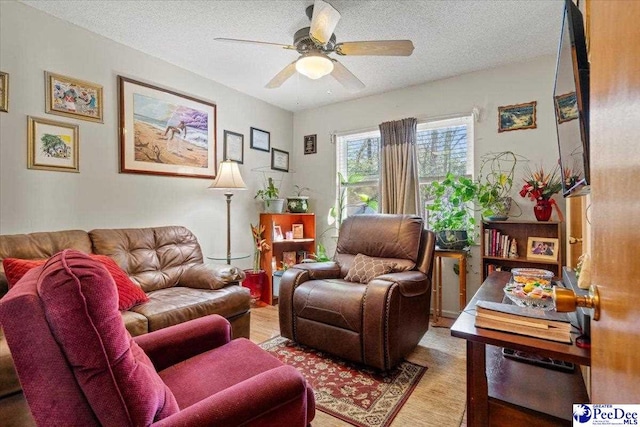 living area featuring ceiling fan, a textured ceiling, and wood finished floors