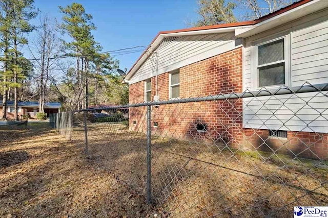 view of property exterior featuring crawl space, brick siding, and fence