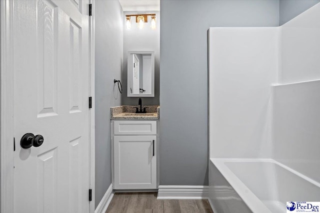 bathroom with hardwood / wood-style flooring, vanity, and a bath