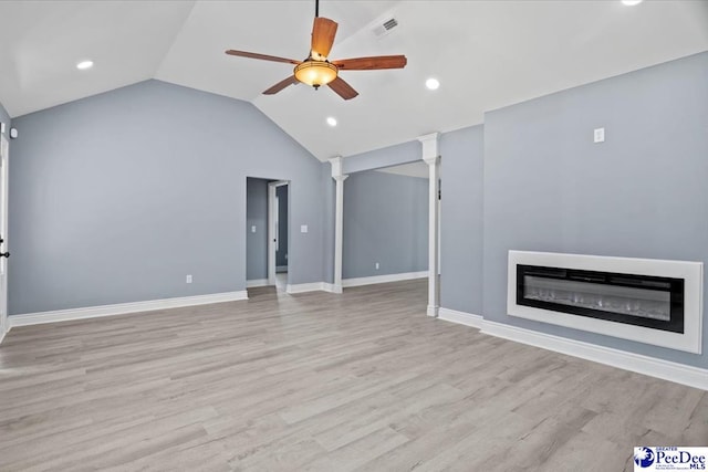 unfurnished living room with ornate columns, vaulted ceiling, ceiling fan, and light hardwood / wood-style floors