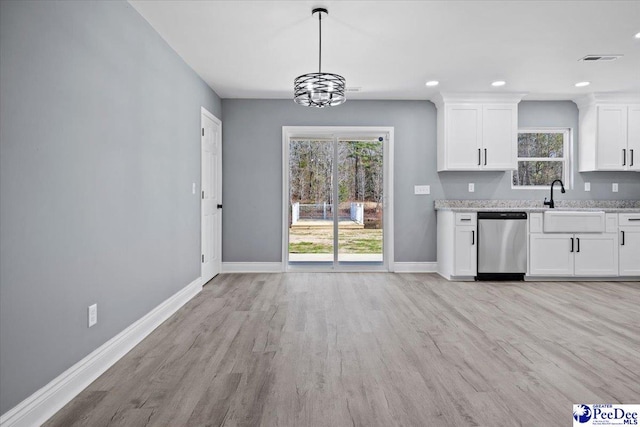 kitchen featuring white cabinetry, hanging light fixtures, stainless steel dishwasher, light stone counters, and light hardwood / wood-style flooring