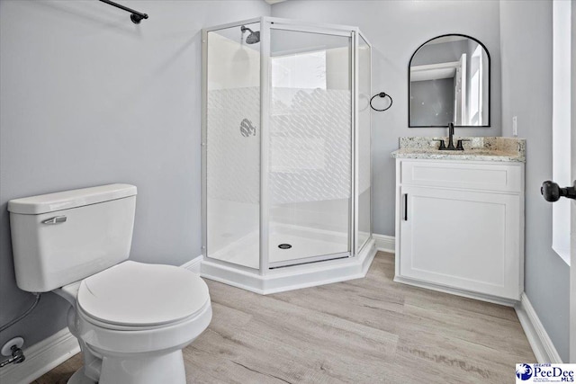 bathroom featuring vanity, hardwood / wood-style flooring, a shower with door, and toilet