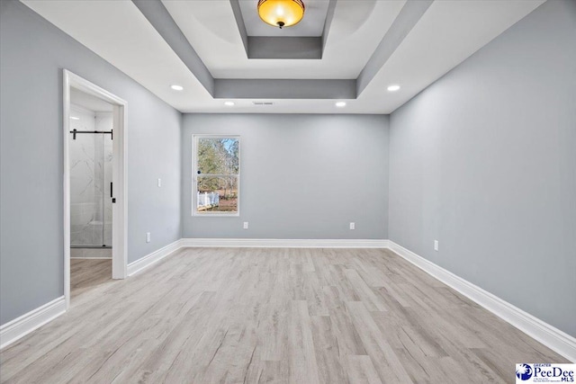 empty room with a raised ceiling and light hardwood / wood-style floors