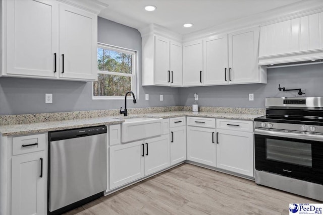 kitchen featuring sink, light wood-type flooring, stainless steel appliances, light stone countertops, and white cabinets