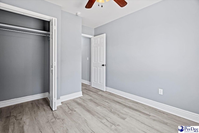 unfurnished bedroom with ceiling fan, light wood-type flooring, and a closet