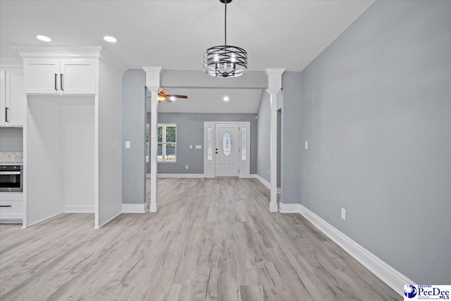 foyer entrance with ceiling fan with notable chandelier, light hardwood / wood-style flooring, and ornate columns