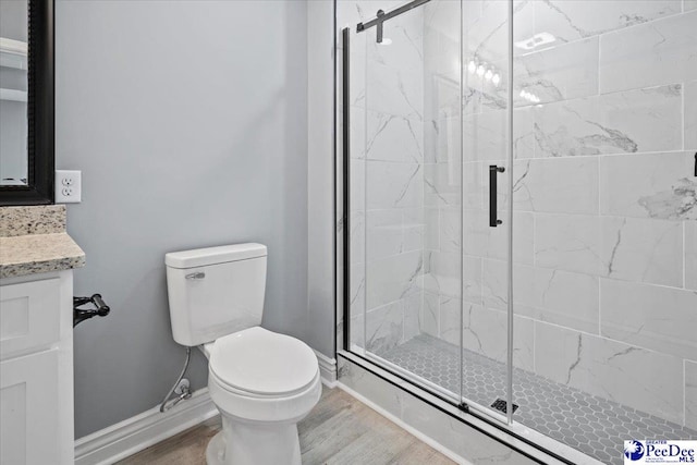 bathroom featuring vanity, wood-type flooring, a shower with shower door, and toilet