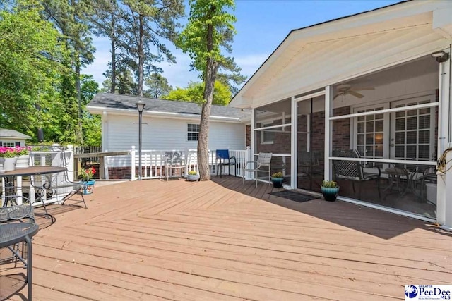 wooden deck featuring a ceiling fan and a sunroom