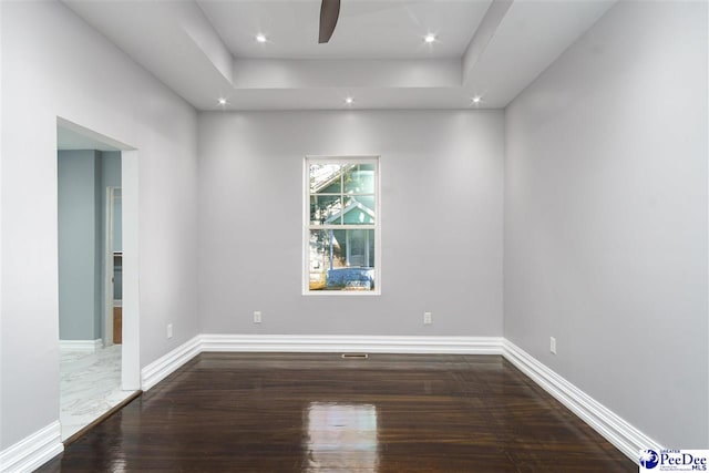 unfurnished room featuring ceiling fan, a raised ceiling, and hardwood / wood-style floors