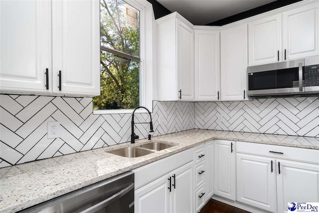 kitchen featuring sink, dishwasher, light stone counters, tasteful backsplash, and white cabinets