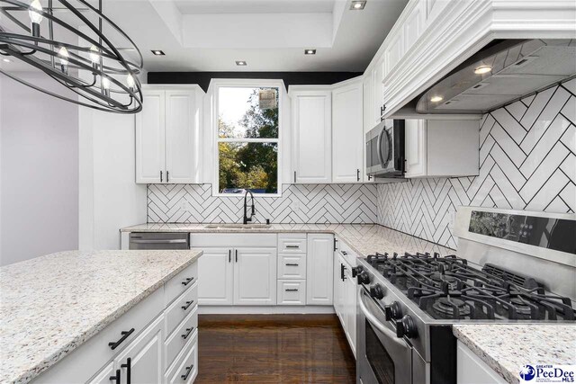 kitchen featuring white cabinetry, appliances with stainless steel finishes, custom range hood, and sink