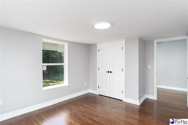 unfurnished bedroom featuring dark hardwood / wood-style floors and a closet