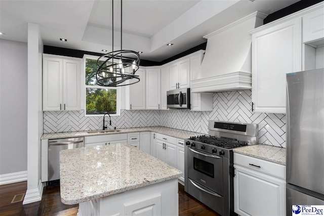 kitchen featuring white cabinetry, sink, hanging light fixtures, a center island, and stainless steel appliances