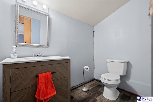 half bath featuring lofted ceiling, vanity, toilet, and wood finished floors