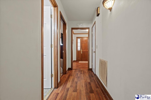 hall featuring wood finished floors, visible vents, and baseboards