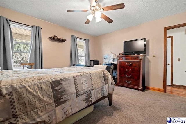 bedroom featuring light carpet, ceiling fan, baseboards, and a textured ceiling