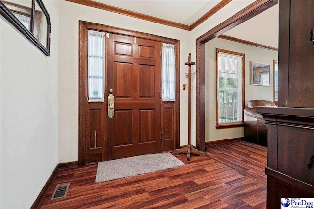 foyer featuring dark wood finished floors, visible vents, crown molding, and baseboards