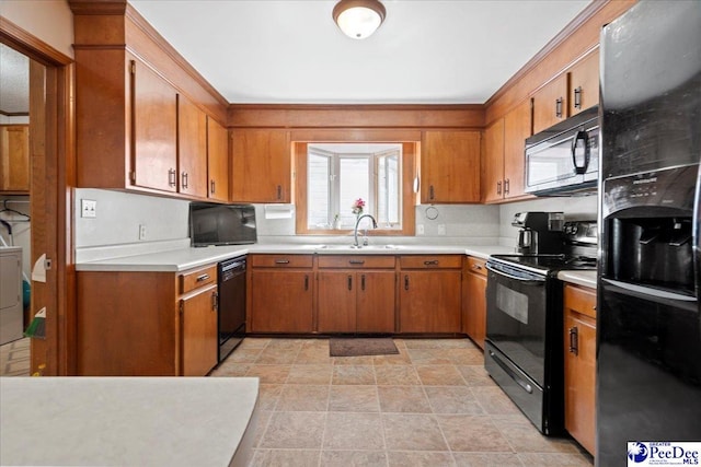 kitchen with brown cabinetry, light countertops, a sink, and black appliances