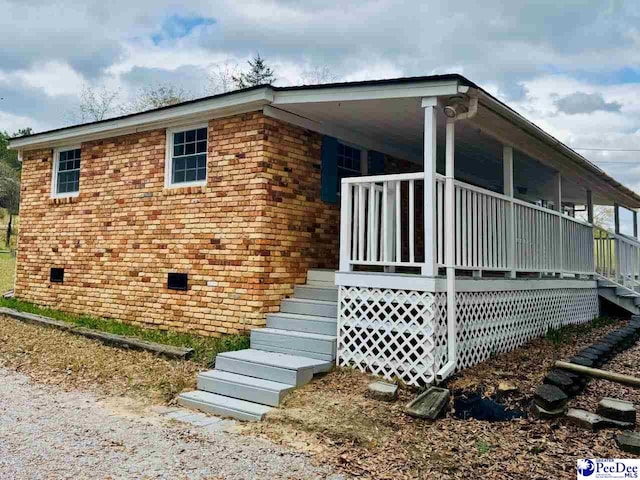 view of side of property featuring brick siding and covered porch