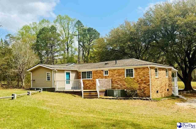 rear view of property featuring central air condition unit, crawl space, brick siding, a wooden deck, and a yard