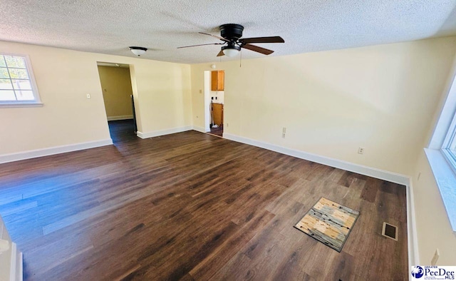 empty room featuring visible vents, ceiling fan, a textured ceiling, and dark wood finished floors