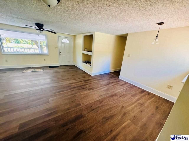 interior space with a textured ceiling, baseboards, dark wood finished floors, and built in shelves